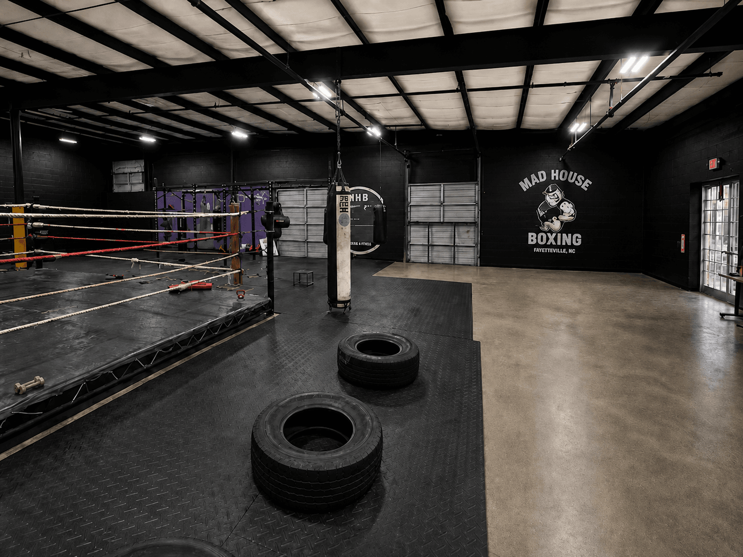 Mad House Boxing Dojo training floor with boxing ring and heavy bags